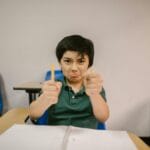 Zaburzenia integracji sensorycznej: jak mogą wpływać na naukę pisania i czytania Chłopiec w klasie sfrustrowany przy ławce, trzyma połamane ołówki