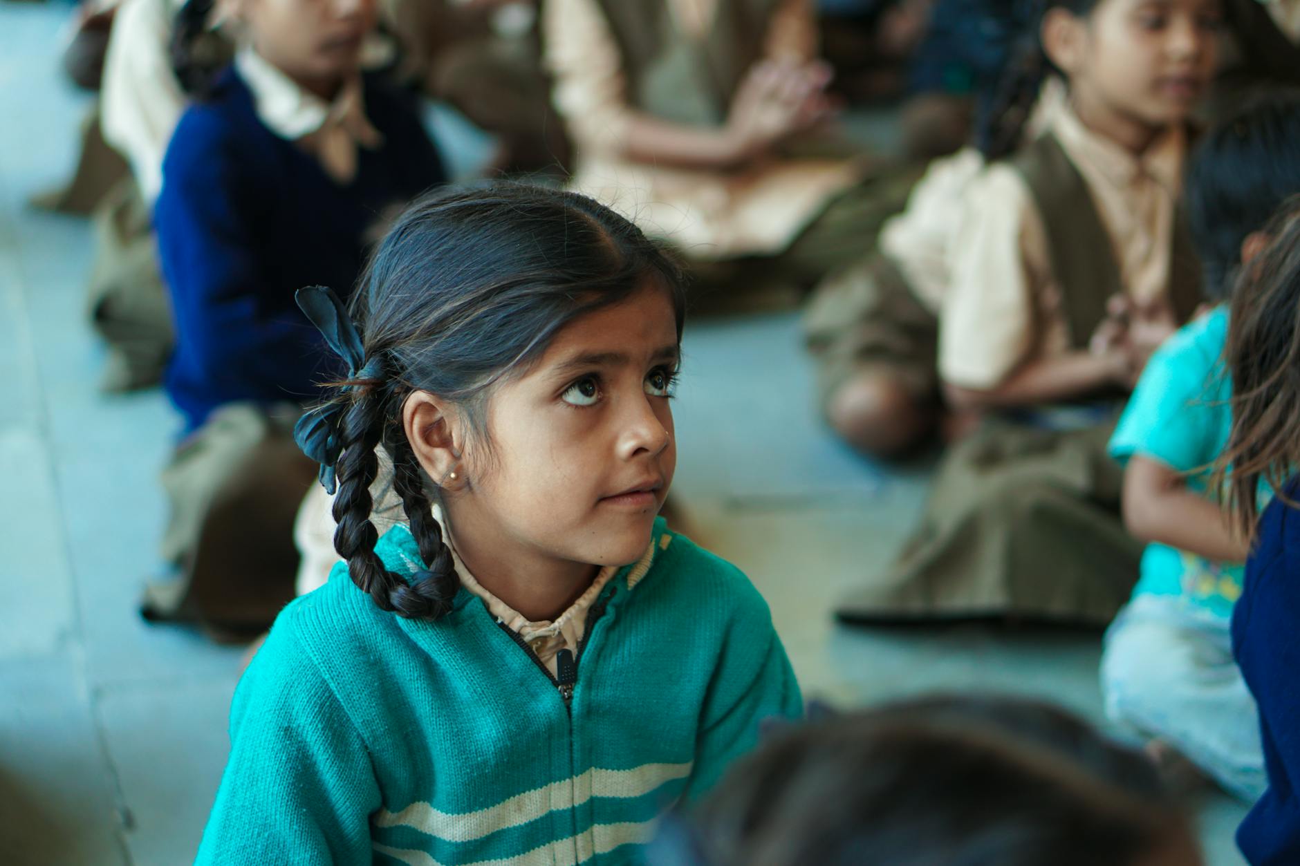 Dziewczynka w klasie uważnie słucha nauczyciela podczas lekcji