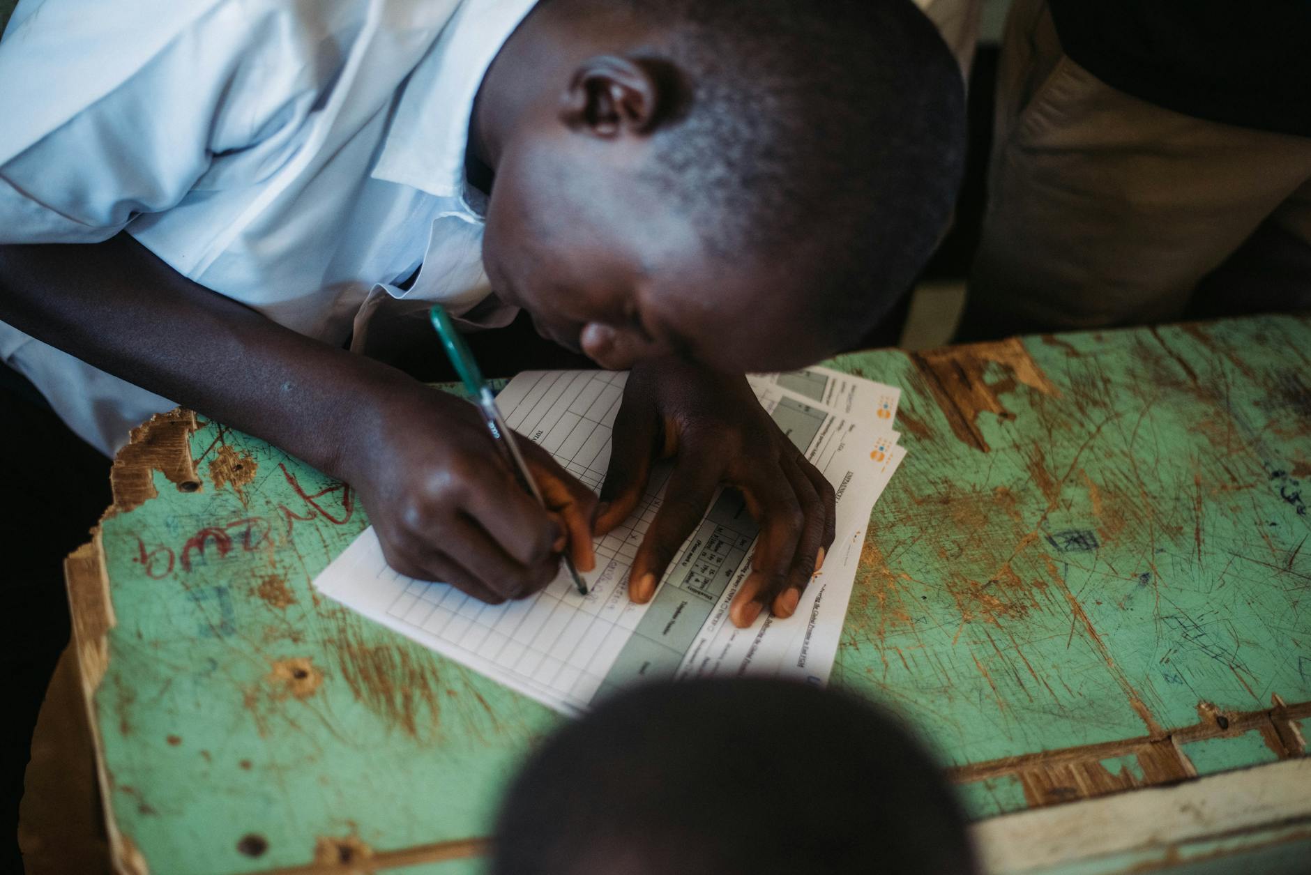 Skupiony uczeń z klas 1–3 pisze w zeszycie podczas lekcji