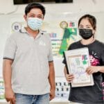 Dwóch azjatyckich uczniów w maseczkach prezentuje materiały edukacyjne