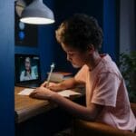 Dziecko uczy się przy biurku z laptopem i notatkami w domu