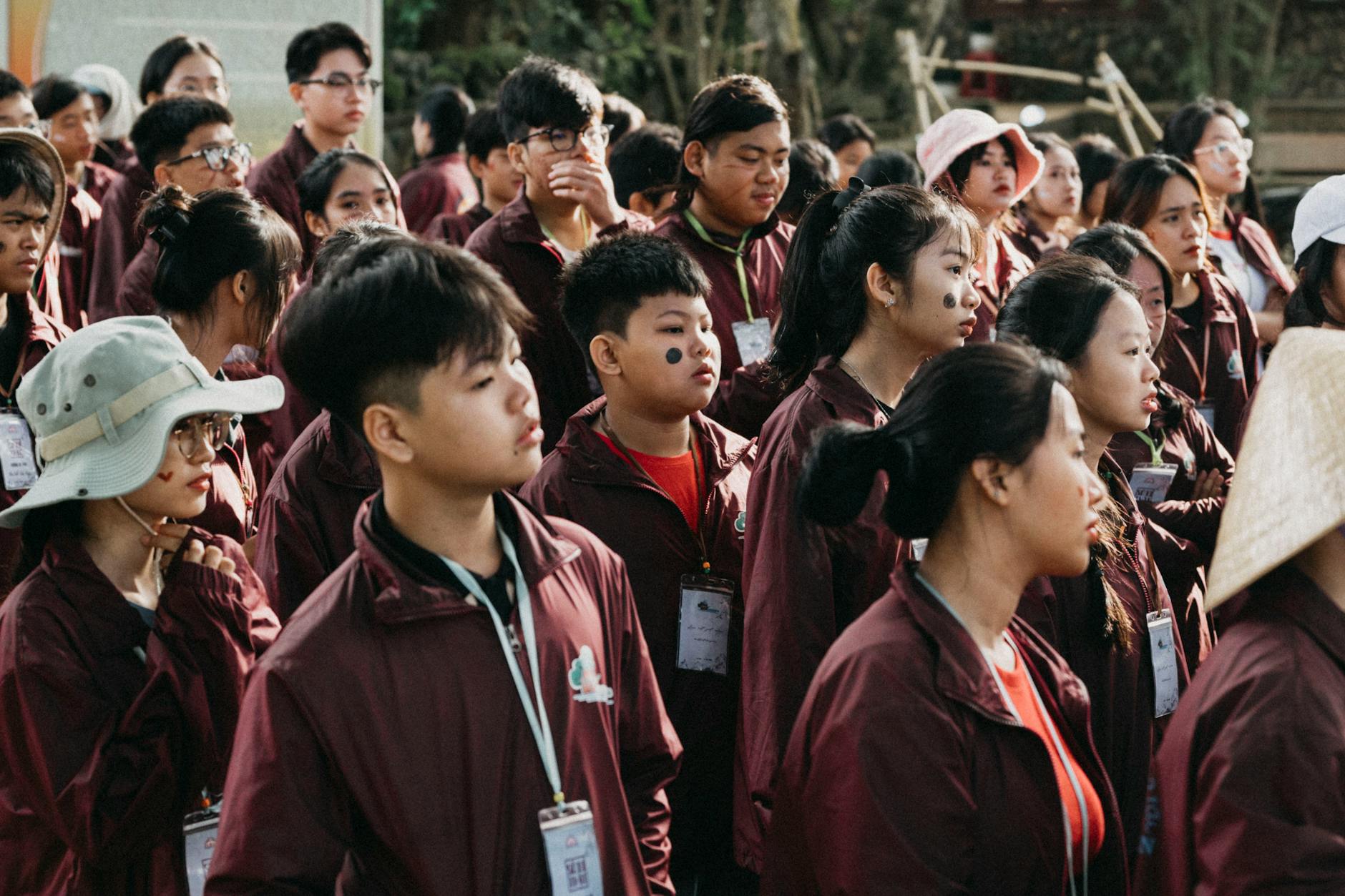 Grupa nastolatków z identyfikatorami uważnie słucha na szkolnej wycieczce