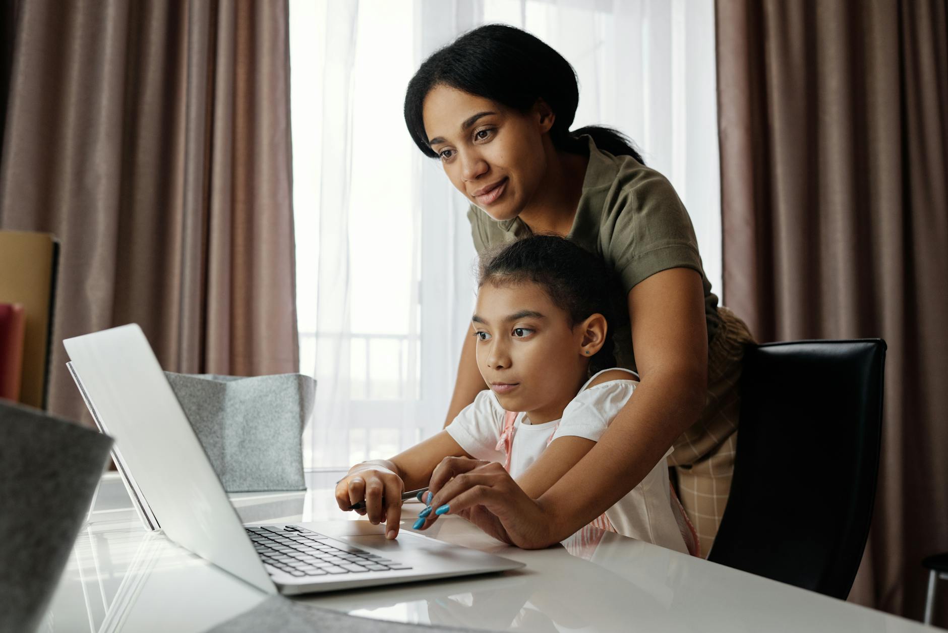 Mama pomaga córce w lekcji online przy laptopie w domu