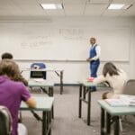 Nauczyciel akademicki nadzoruje studentów piszących egzamin