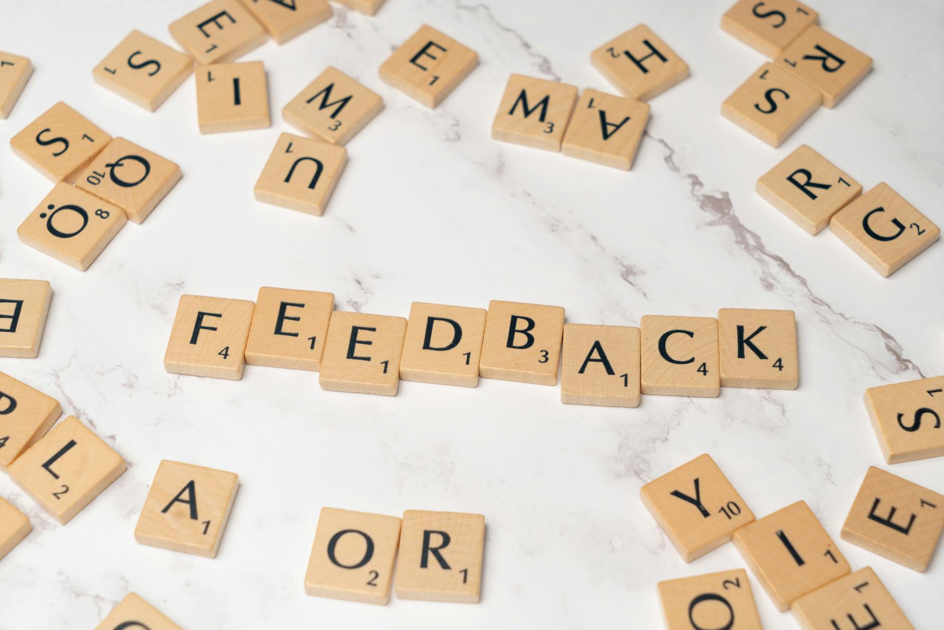 Drewniane płytki Scrabble układające się w słowo feedback na marmurze