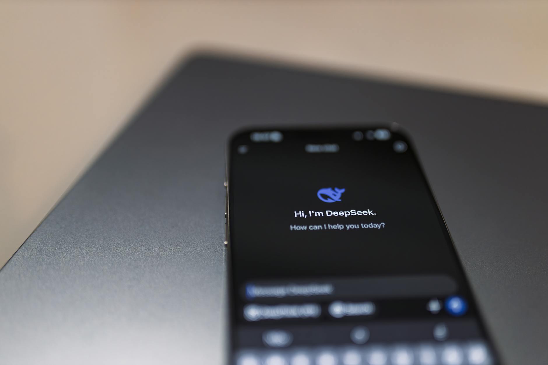 Smartfon z interfejsem asystenta AI leżący na klawiaturze laptopa