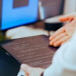 Kiedy Allegro ma obowiązek odblokować konto Programista analizuje kod na tablecie w nowoczesnym biurze