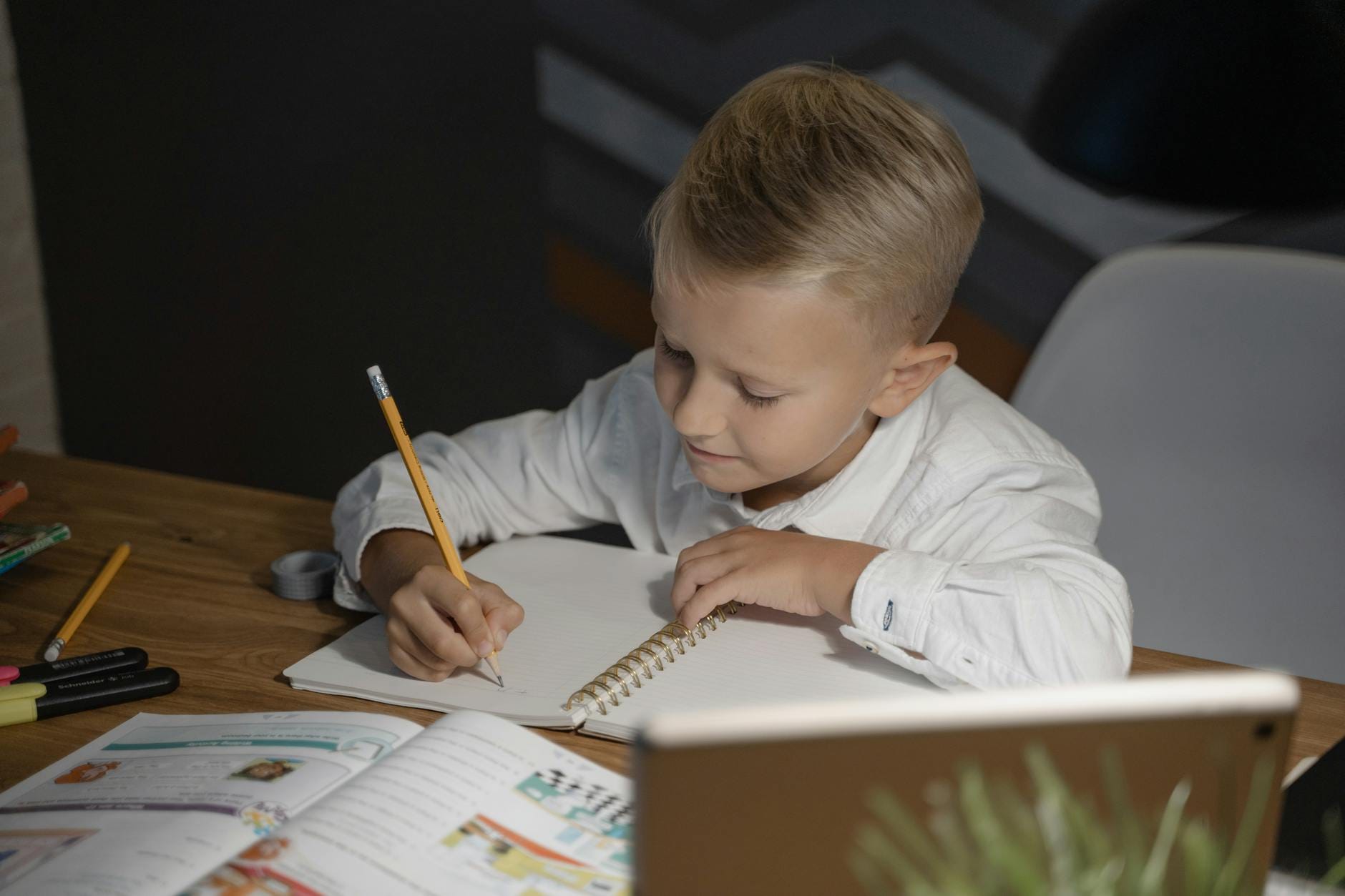 Chłopiec w wieku szkolnym odrabia lekcje przy biurku w domu