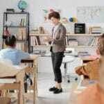 Liczba nauczycieli w Polsce: ile etatów, ile wakatów i gdzie brakuje kadr Nauczyciel prowadzi lekcję w klasie pełnej uważnych uczniów
