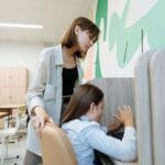 Jak rozpoznawać i wspierać ucznia z dysleksją, gdy brakuje czasu na diagnozę w szkole Nauczycielka pomaga uczniowi przy komputerze w jasnej klasie