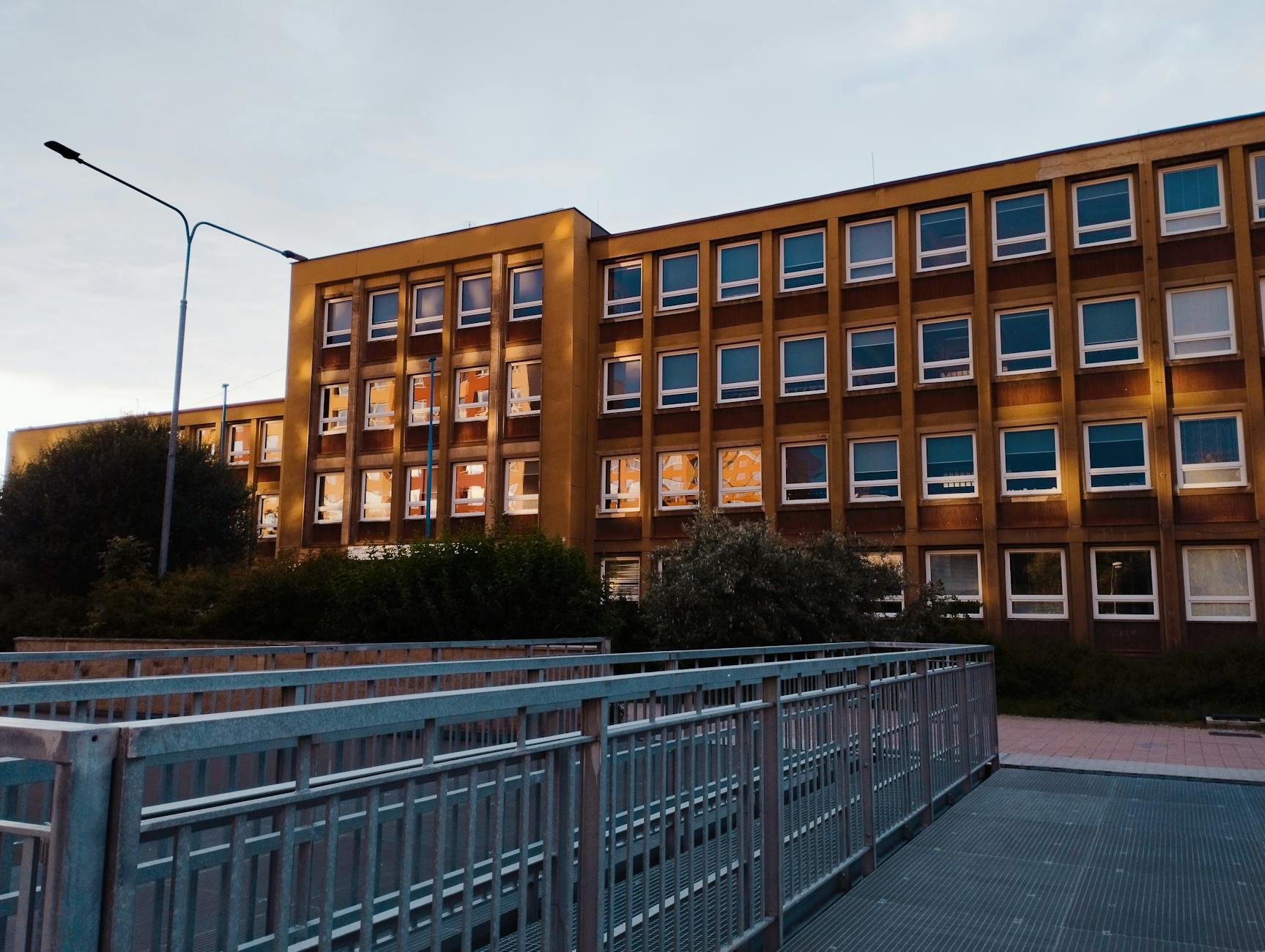 Nowoczesny budynek szkoły oświetlony o zmierzchu z chodnikiem z przodu