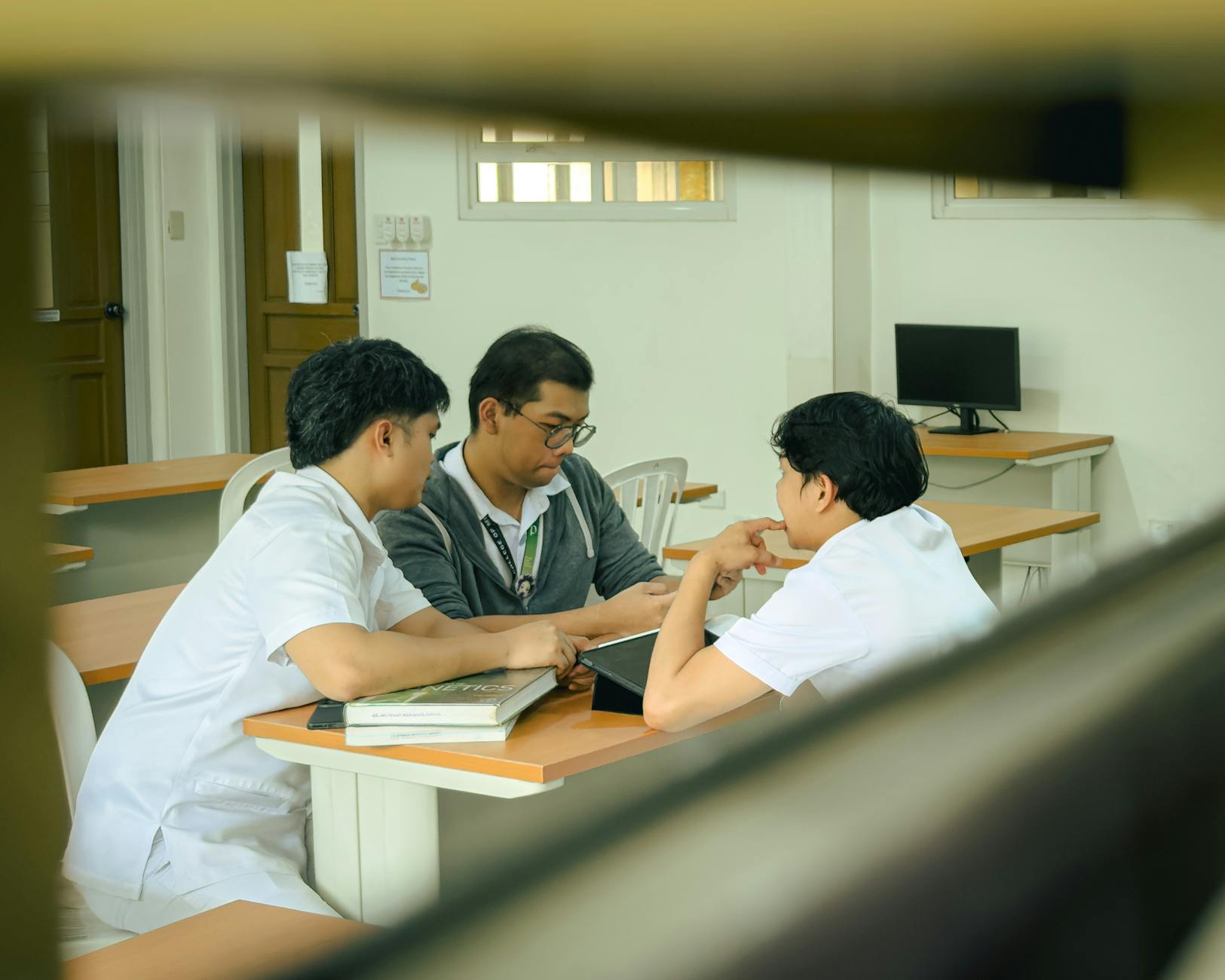 Troje uczniów pracuje wspólnie nad projektem w szkolnej klasie