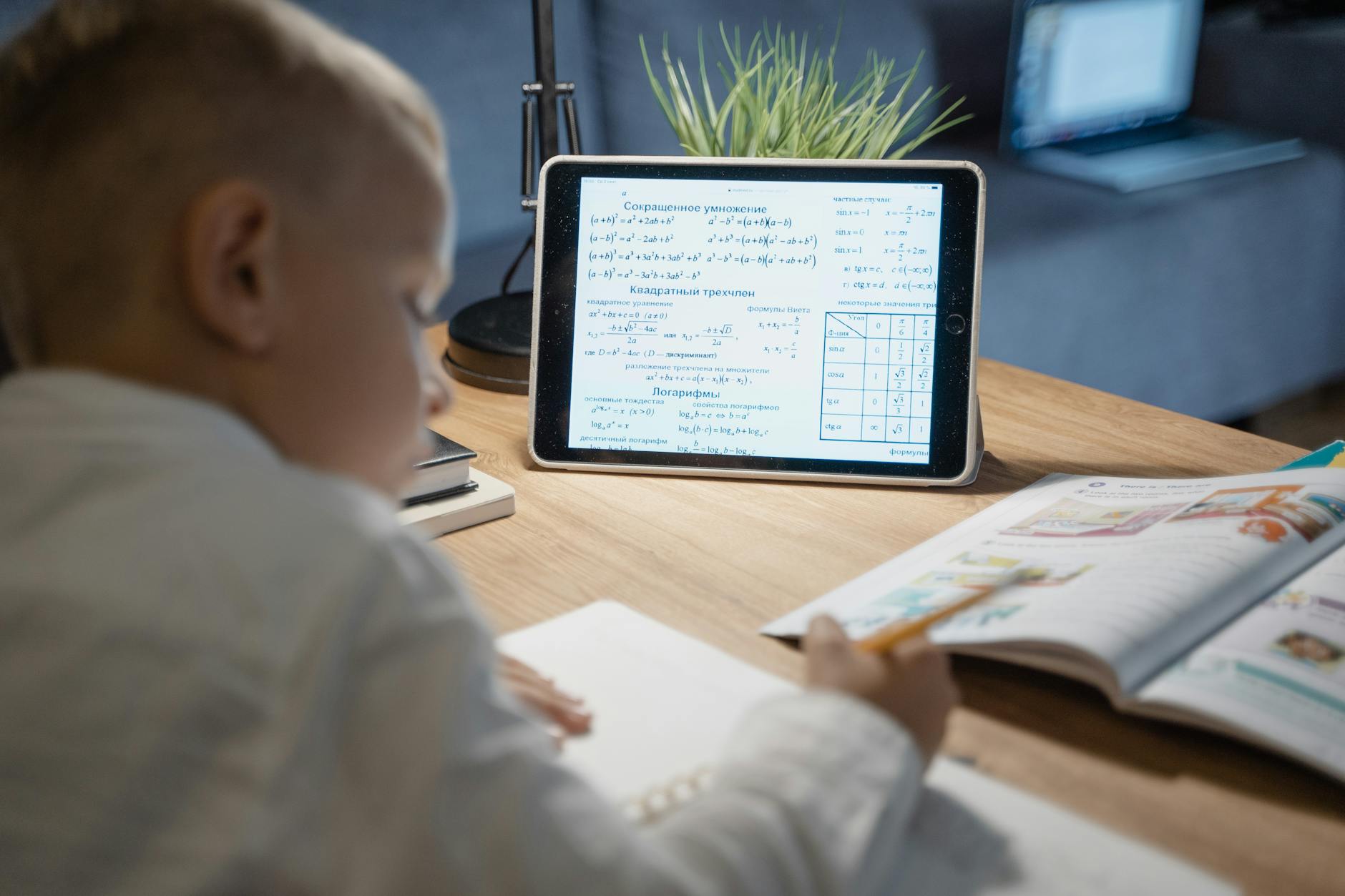Chłopiec uczy się matematyki na tablecie przy biurku w domu
