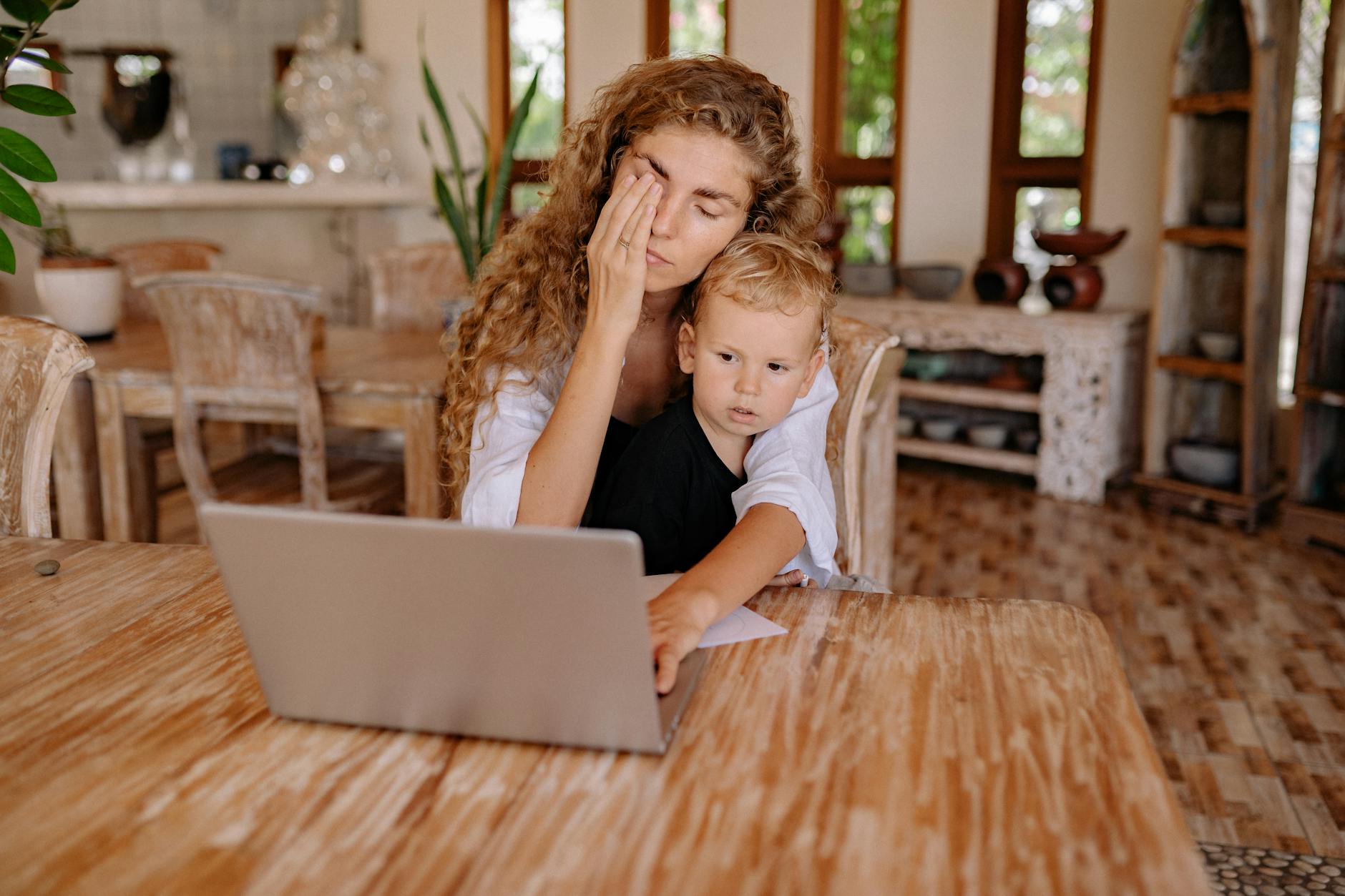 Mama pracująca przy laptopie w domu obok spokojnie bawiącego się dziecka